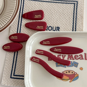 Set di 8 fermagli per capelli vintage rosso scuro con scritte dorate su un piatto