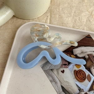Macro detail of wave shark hair clip with blue and cream marble acetate pattern