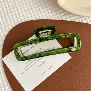 Macro view of green marble acetate hair claw clip with golden spring on a poem card