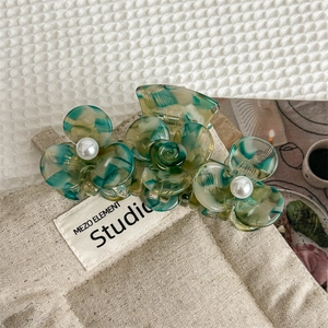 Detailed macro view of acetate floral hair claw with marble texture and pearl center