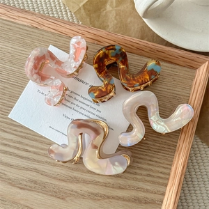 Set of four wavy acetate claw clips in blue, amber, and pastel marble patterns