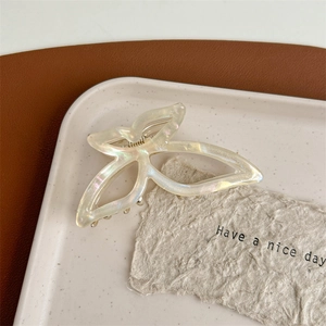 Detail of elegant acetate bow hair claw clip with pearlescent finish on decorative tray