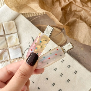 Elegant acetate hair clips set with colorful rhinestones for women, warm beige background