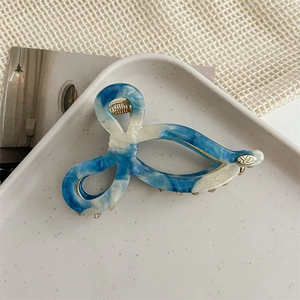 Detailed macro shot of marble textured blue and white bow hair claw on ceramic tray