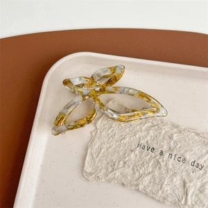 Detailed close-up of butterfly claw clip with gold and beige marble textured acetate material
