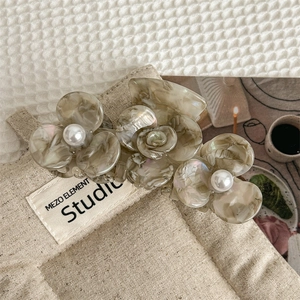 Detail of acetate floral hair claw clip with marble texture and pearl embellishment
