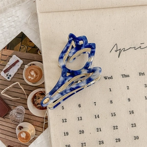 Detalle de la pinza para el cabello de tulipa en acetato jaspeado azul y metal dorado