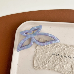 Detail of a purple marble acetate butterfly hair claw clip on a ceramic tray