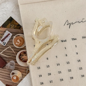 Detalle de la pinza de tulipán en acetato crema con resorte dorado y logotipo