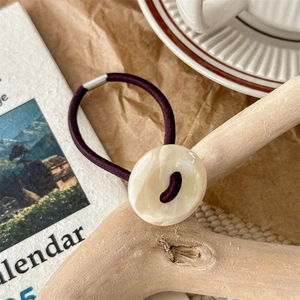 Detailed shot of an elastic hair tie featuring a large marble-textured resin button detail