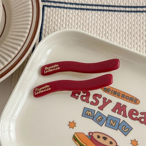 Dettaglio di fermagli per capelli ondulati rossi con logo Barrette LaFrance dorato