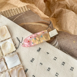 Detailed macro view of acetate hair clip with colorful rhinestones on vintage background