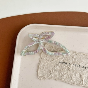 Macro view of butterfly acetate hair claw clip with purple marble pattern and gold metal frame