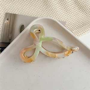 Detail of colorful marble acetate hair claw clip with golden logo and metal spring