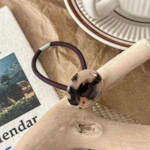 Close-up of a high-elastic purple hair tie with a round amber tortoiseshell resin button