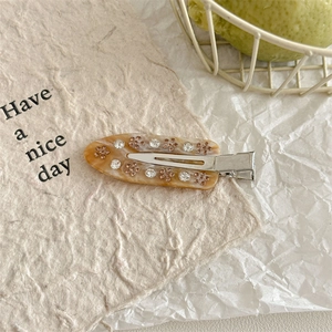 Detail view of amber marble acetate hair clip with pink rhinestone flower inlay and silver metal grip