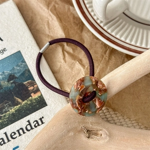 Detail of durable elastic hair tie with marble resin button in a vintage setup