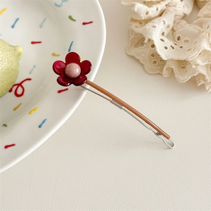 Nahaufnahme der Vintage-Blumenhaarklammer mit dunkelroten Blüten und Metallclip