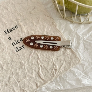 Close-up of brown acrylic hair clip featuring sparkling rhinestone flower patterns