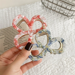 Elegant bow-shaped acetate hair claw clips with marble texture and gold metal trim