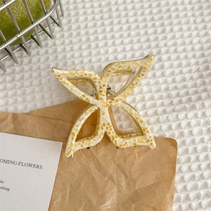 Gros plan sur la pince à cheveux papillon en acétate jaune avec motif marbré