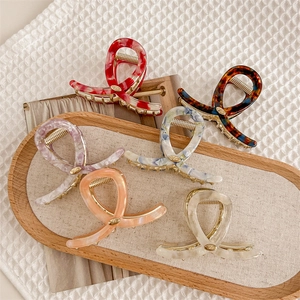 Lot de six pinces à cheveux texturées marbrées aux tons chauds sur un plateau beige
