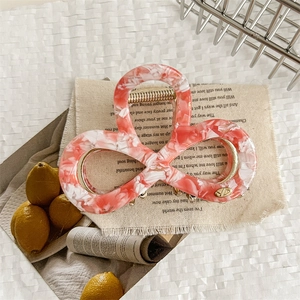 Close-up of pink and white marble acrylic hair claw with strong gold metal spring