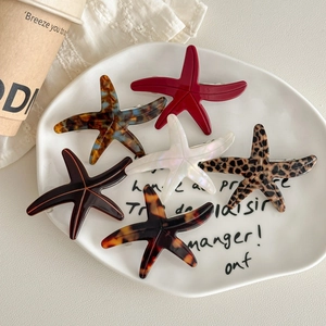 Starfish shaped acetate hair clips in various colors displayed in a decorative ceramic bowl