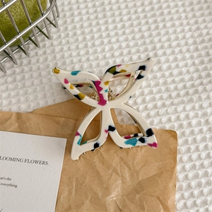 Gros plan d'une pince à cheveux papillon aux textures colorées sur tissu gaufré