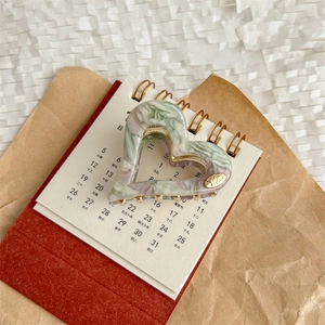 Détail de la pince à cheveux cœur en marbre avec logo YD sur un calendrier stylé