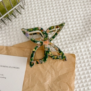 Détail de la pince à cheveux papillon avec motif floral en acétate et ressort en métal