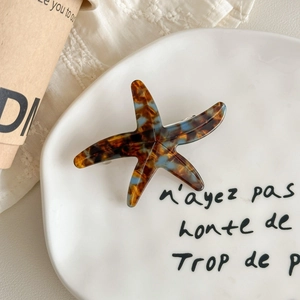 Detailed macro view of starfish acetate hair clip with tortoise shell pattern in blue and amber