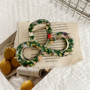 Detail of floral resin hair claw clip with colorful patterns and gold metal spring