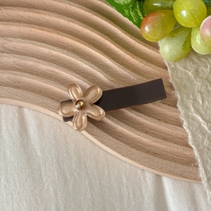 Close-up of translucent blue flower hair clip with a rhinestone on a wooden tray