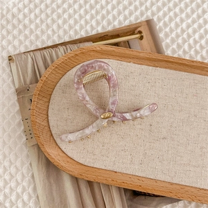 Détail d'une pince à cheveux en acétate marbré rose et violet avec charnière dorée