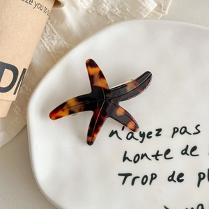 Detail of starfish hair clip with tortoiseshell pattern on a ceramic plate
