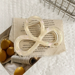 Detail of elegant cream aurora butterfly hair claw clip with a refined metallic logo accent
