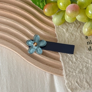 Detailed view of translucent blue floral hair clip on a minimalist wooden tray