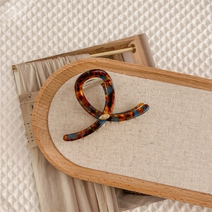 Détail de la pince à cheveux en acétate à motif écaille avec ressort doré en métal