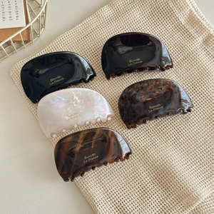 Five assorted vintage acetate shark hair claws with elegant golden French lettering