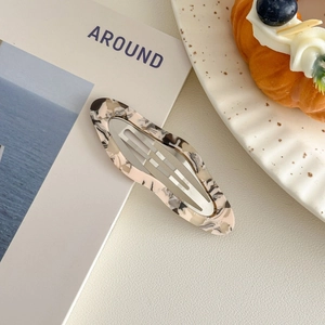 Detail of oval acetate hair clip with vintage oil painting marble texture on magazines