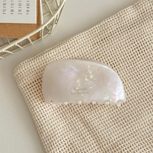 Detail of elegant acetate hair claw clip with pearlescent finish and French text