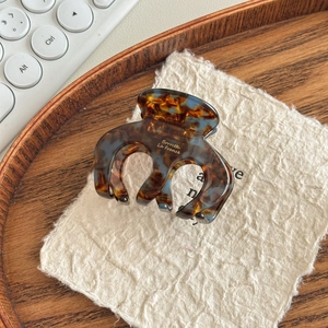 Detailed shot of tortoiseshell hair claw clip with Barrette La France text in wooden tray
