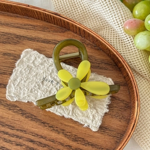 Détail de la pince à cheveux fleur vert olive posée sur un plateau en bois rustique