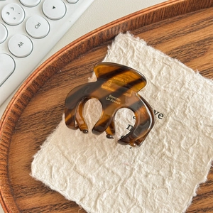 Close-up of tortoise shell hair claw clip with polished finish on a wooden tray