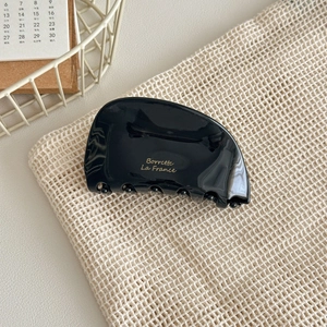Detail showing high-gloss black acetate hair claw clip with golden Barrette La France text