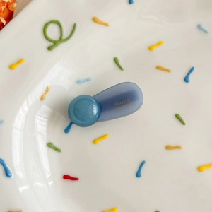 Macro shot of a blue translucent ball-shaped hair clip with gold France Handmade logo
