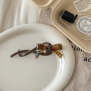 Detail of tortoiseshell resin bow hair clip with gold handmade inscription