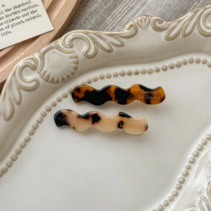 Detail showing two wavy acetate hair barrettes with classic tortoiseshell textures