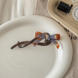 Detail of tortoiseshell bow hair clip with France Handmade gold logo on a white plate